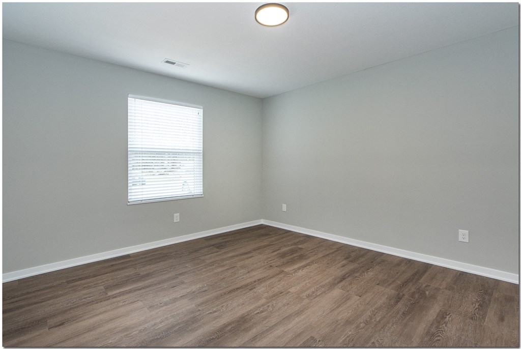 an empty room with wood floors and a window