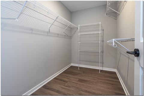 a spacious walk in closet with a large white closet and a ladder in the corner