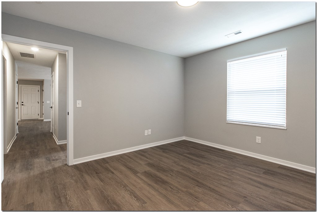 an empty living room with wooden floors and a large window