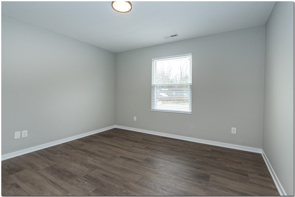 an empty room with wood floors and a window