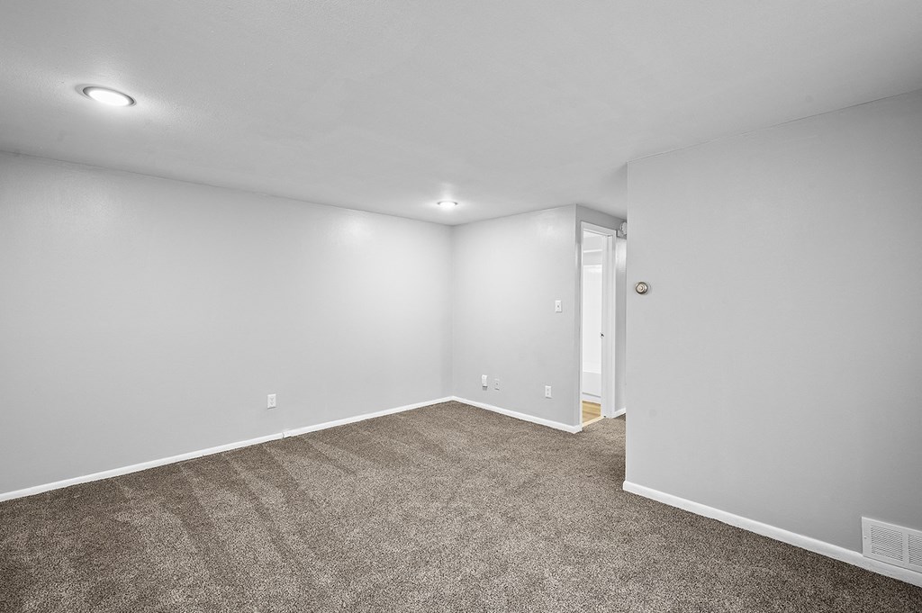 an empty living room with carpet and white walls
