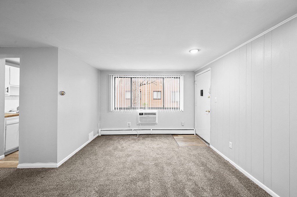 a spacious living room with white walls and a window