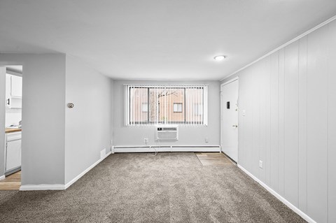 a spacious living room with white walls and a window