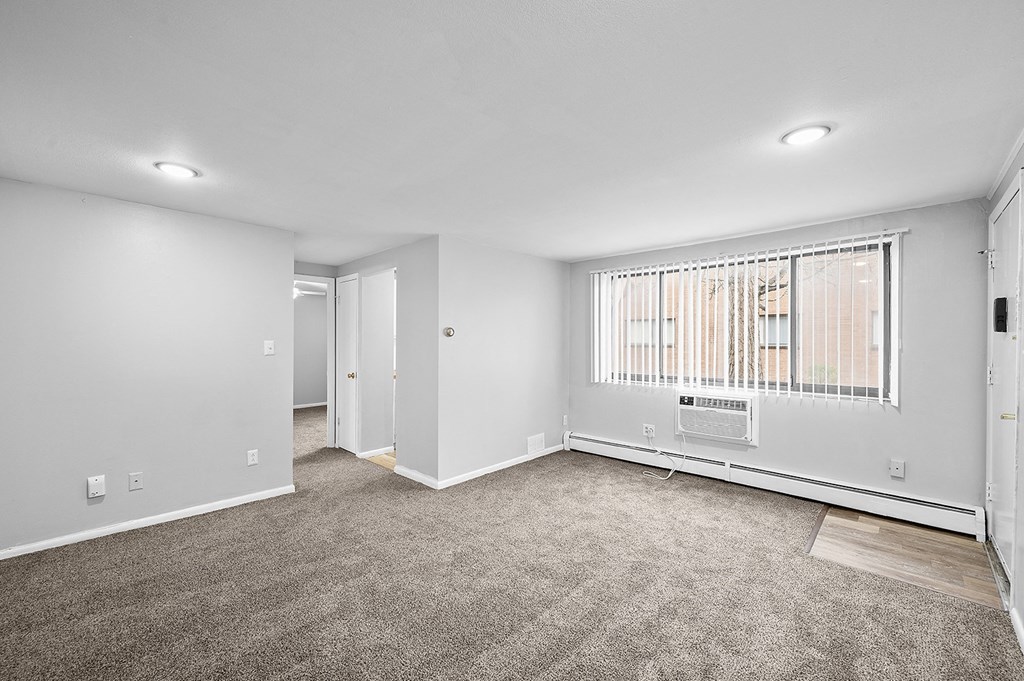 an empty living room with a large window and carpet
