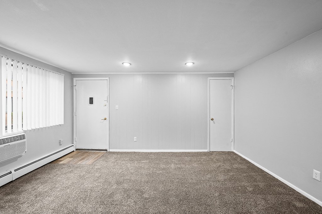 an empty living room with carpet and white walls