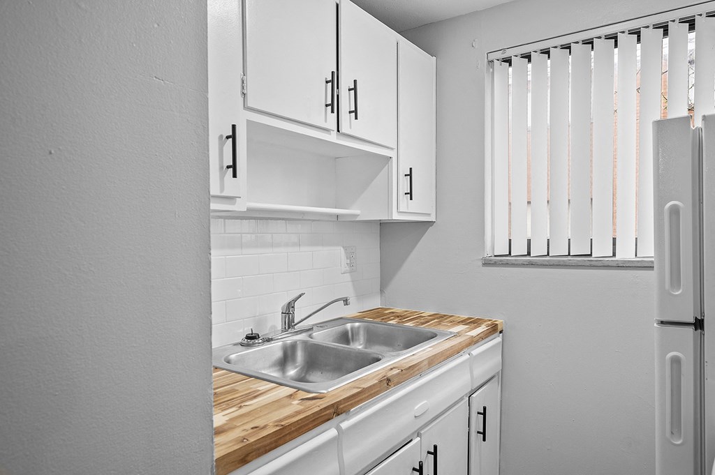 the kitchen of our studio apartment has a sink and white cabinets