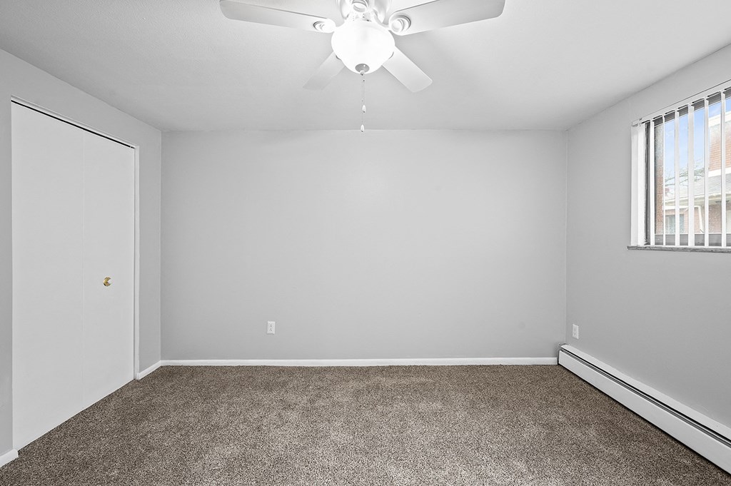 an empty room with carpet and a ceiling fan