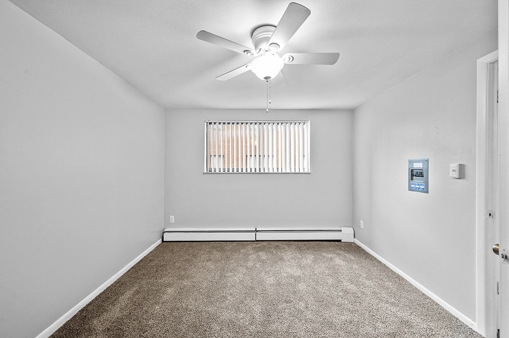 an empty room with a ceiling fan and a window