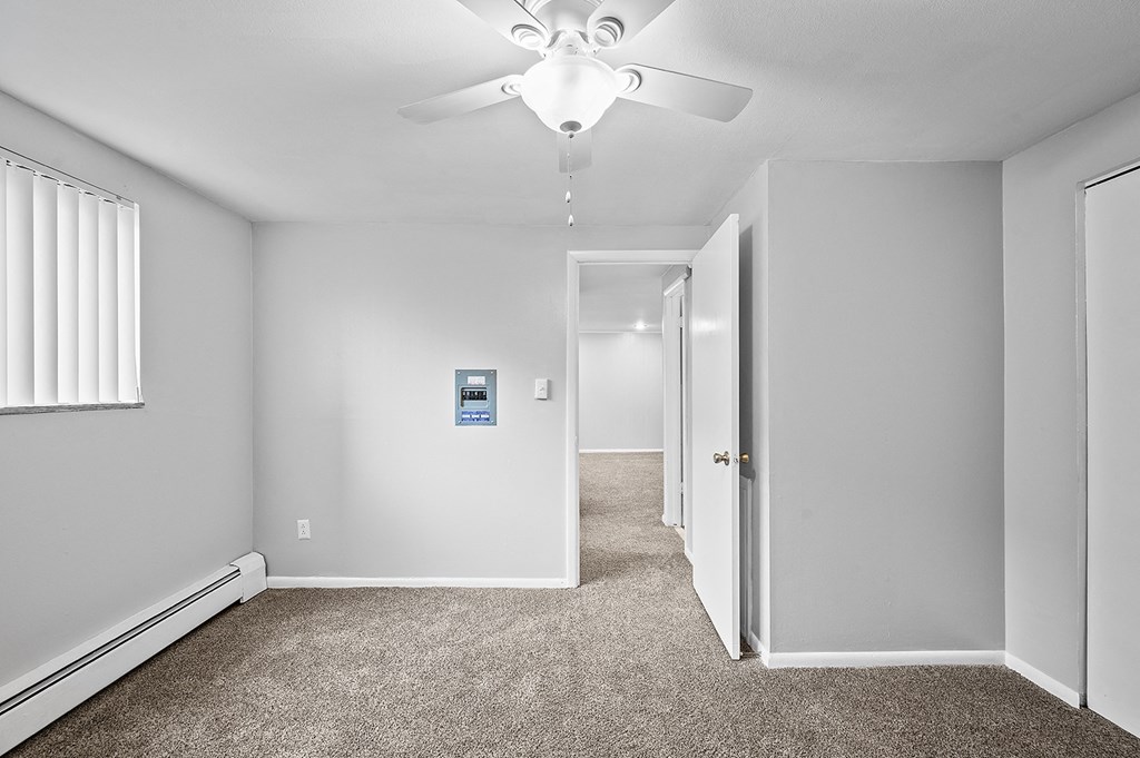 an empty room with carpet and a ceiling fan