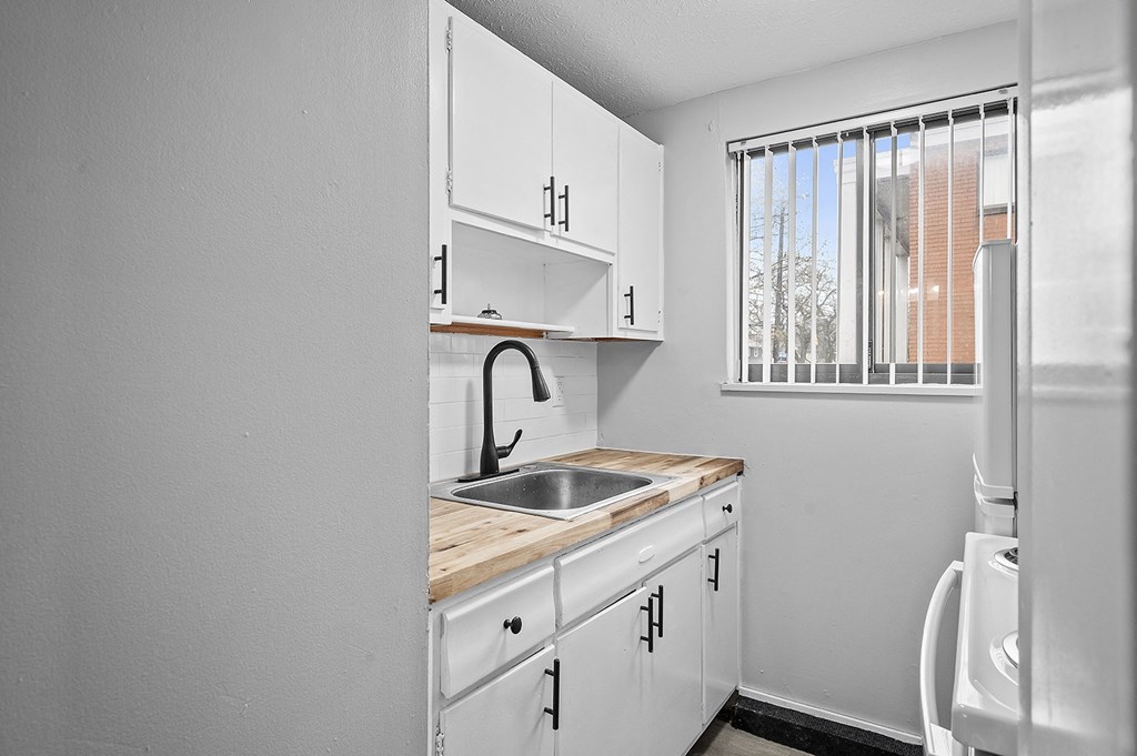 an empty kitchen with white cabinets and a window