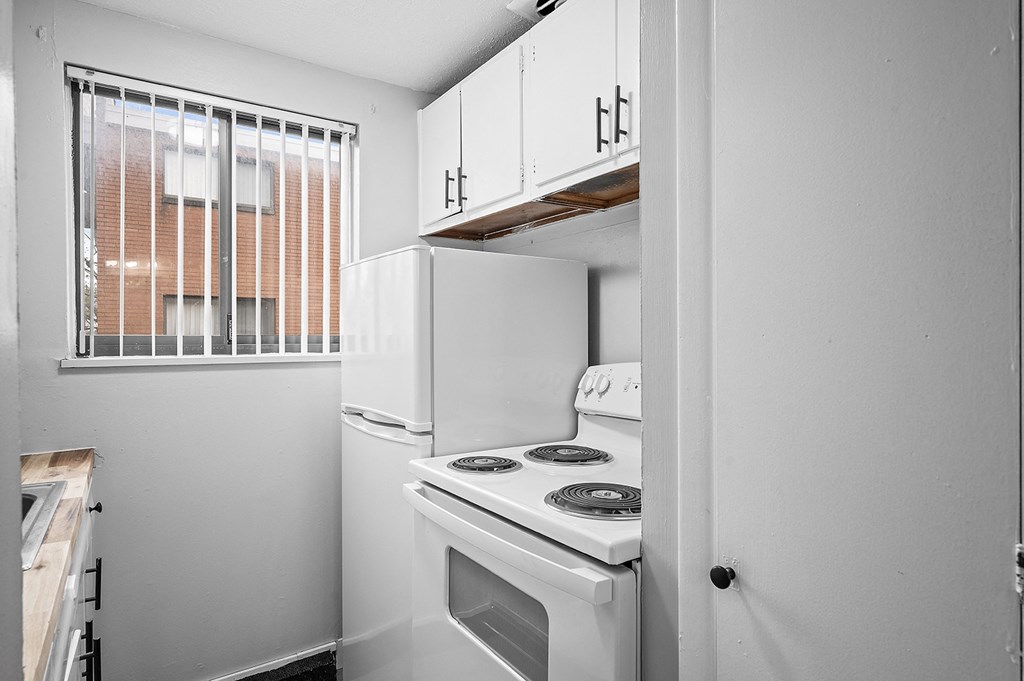 a kitchen with a white stove and refrigerator and a window
