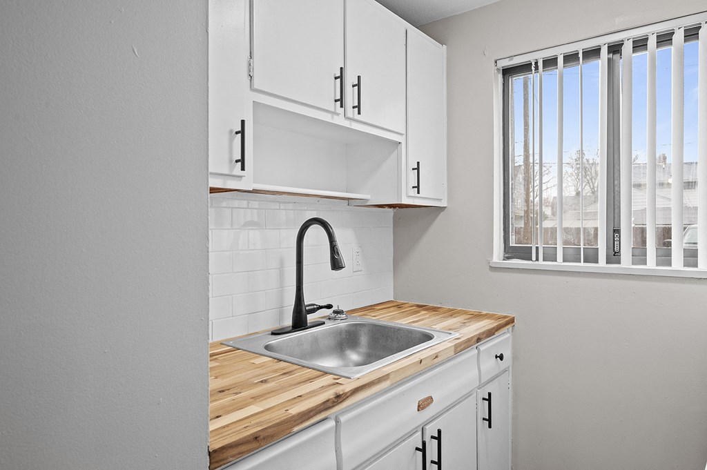a kitchen with white cabinets and a sink and a window