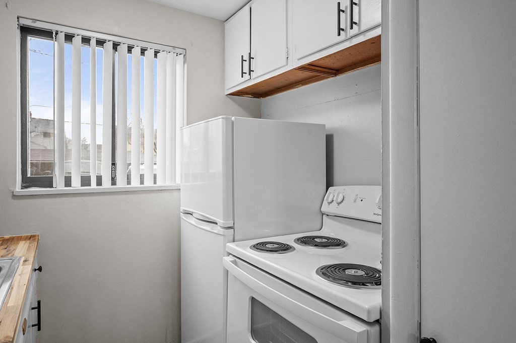 a kitchen with a white stove and refrigerator and a window