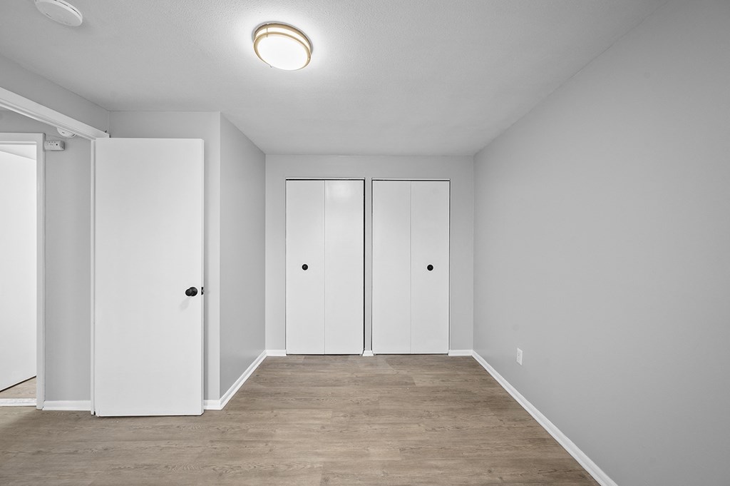 a room with white walls and a wood floor and white closet doors