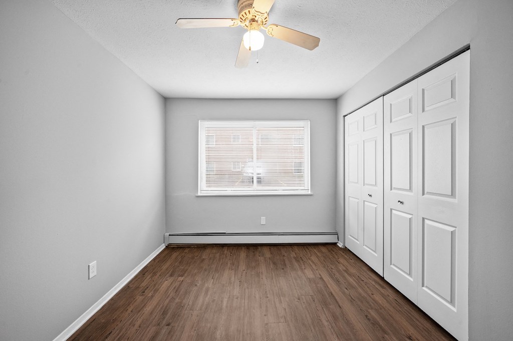 an empty bedroom with a ceiling fan and a window