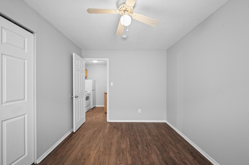 a spacious living room with white walls and a ceiling fan