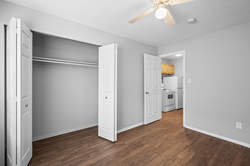 an empty living room with wood flooring and a ceiling fan