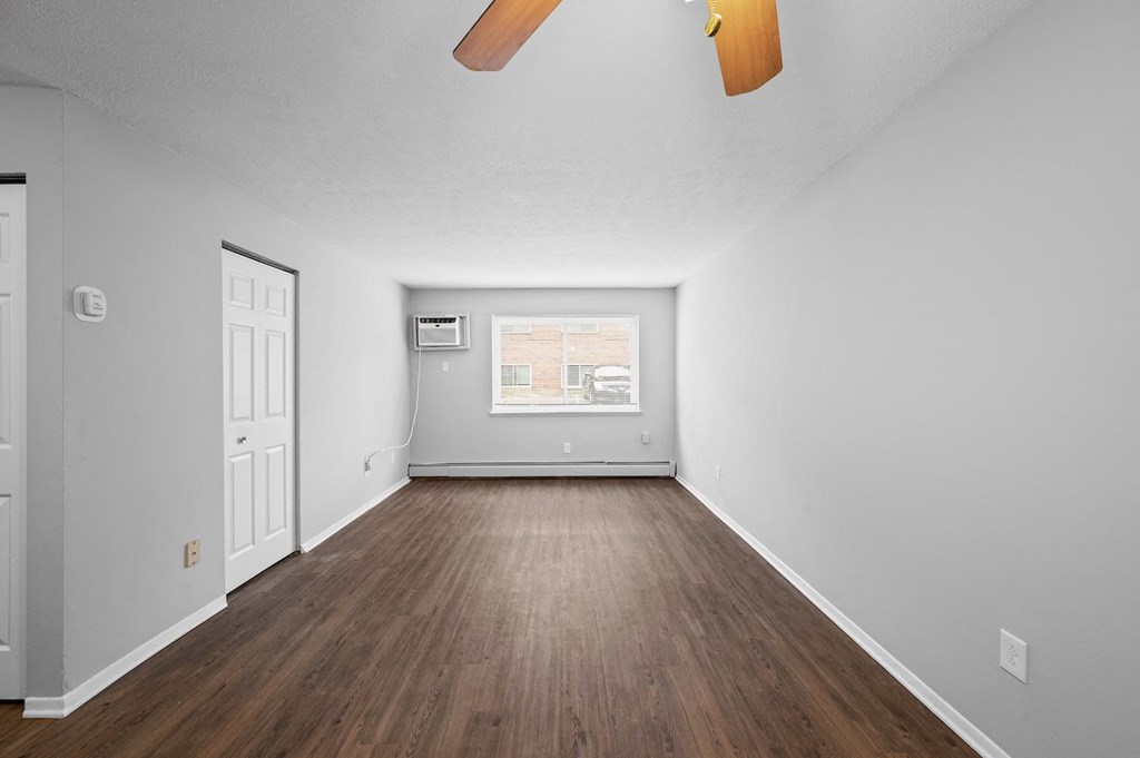 the living room is empty and has white walls and wood floors