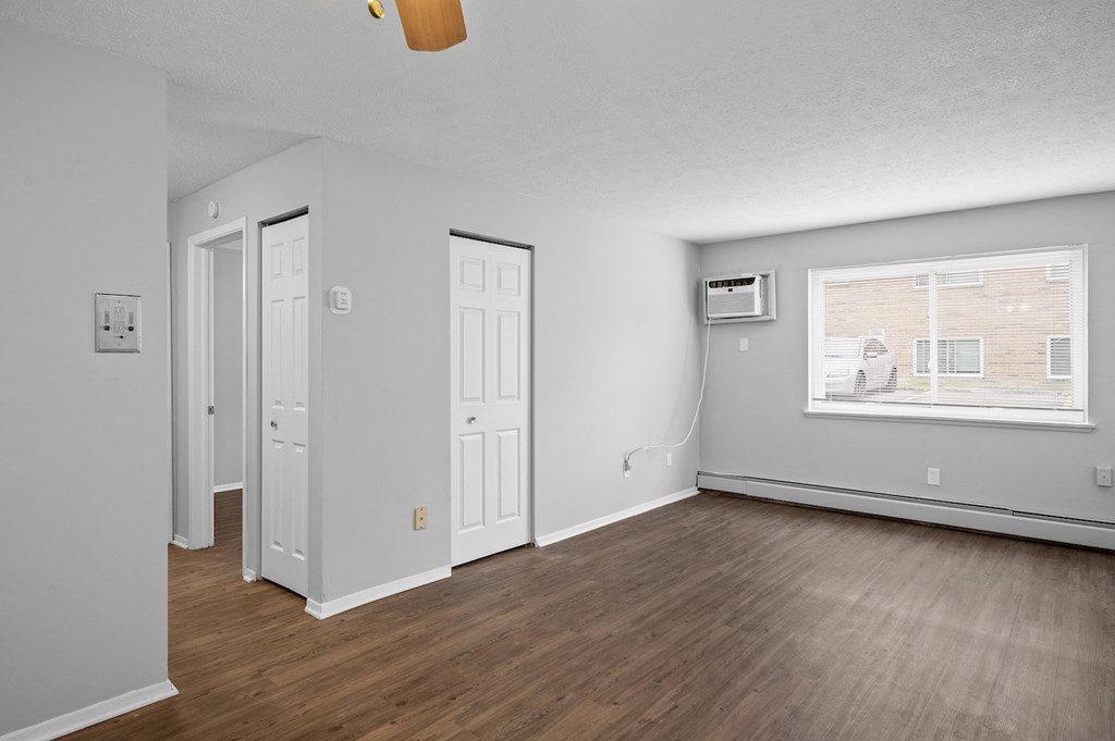 the living room of an apartment with wood flooring and a window