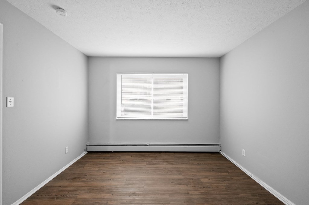 an empty room with wood floors and a window