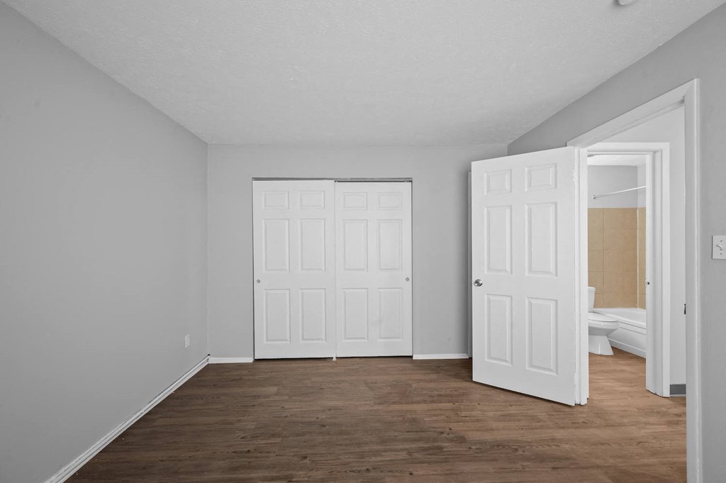 an empty room with white walls and a door to a bedroom