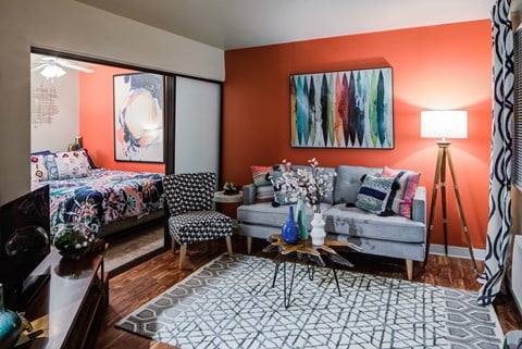 a living room with orange walls and a couch and a bed