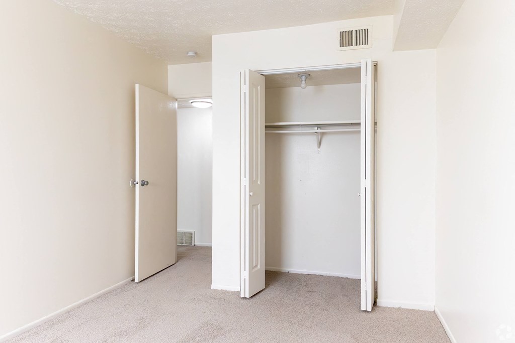 an empty bedroom with a closet and an open door