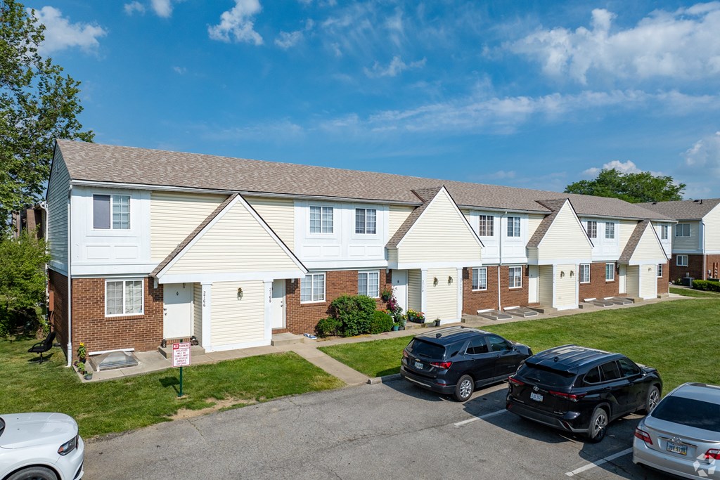 A row of houses with cars parked in front.