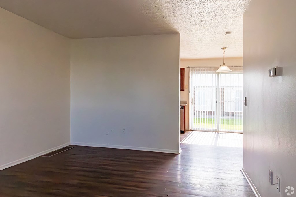 an empty living room with white walls and a wood floor