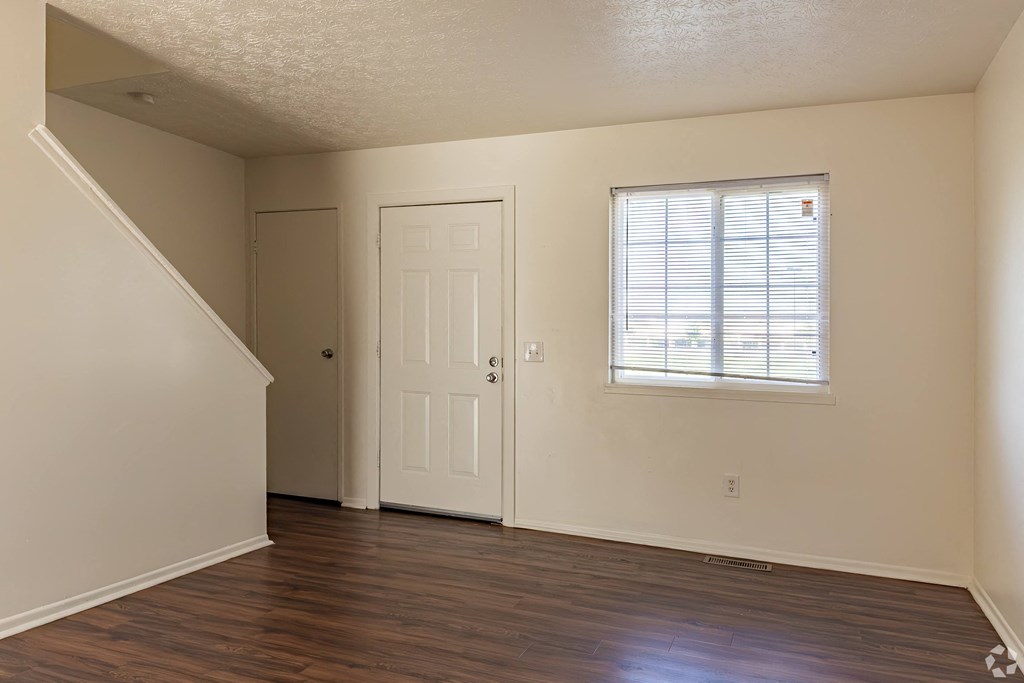 an empty living room with a door and a window