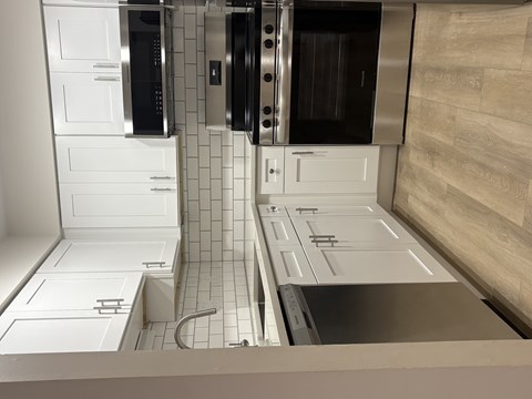 A kitchen with white cabinets and a stainless steel counter.