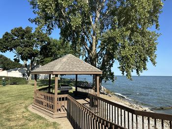 A gazebo sits on a wooden deck overlooking a body of water.