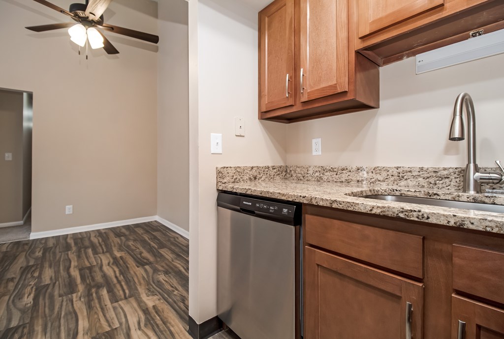 A kitchen with wooden cabinets and a stainless steel dishwasher.
