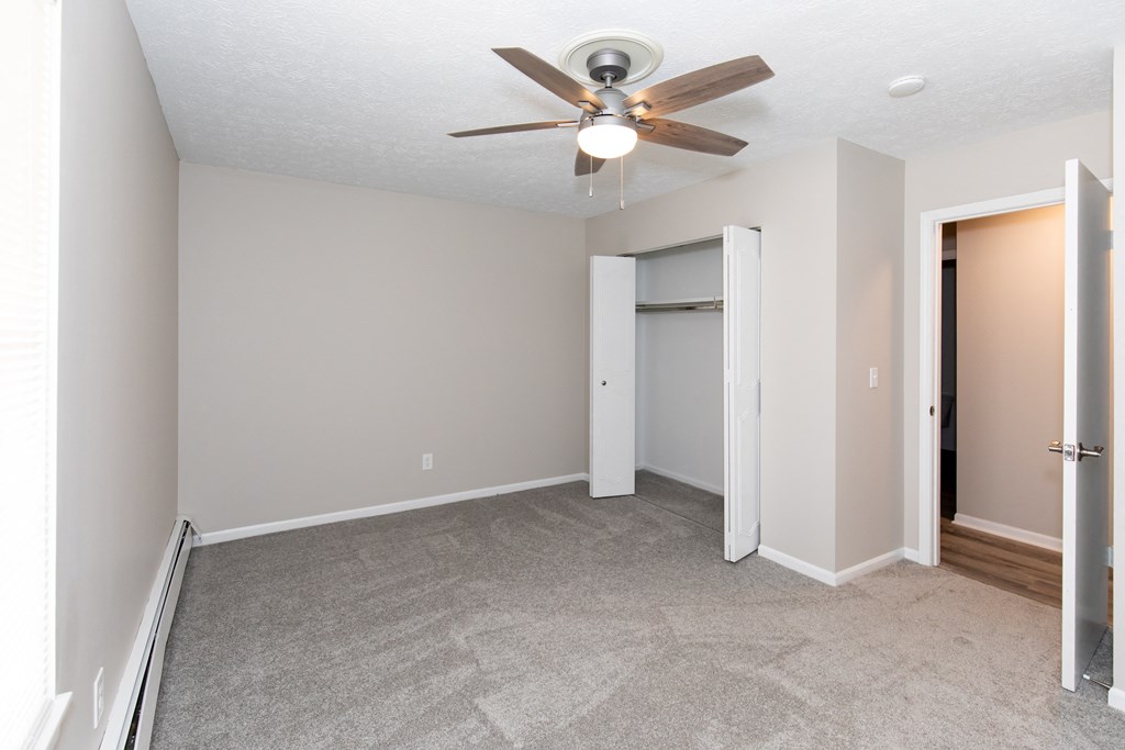 an empty living room with a ceiling fan and a closet