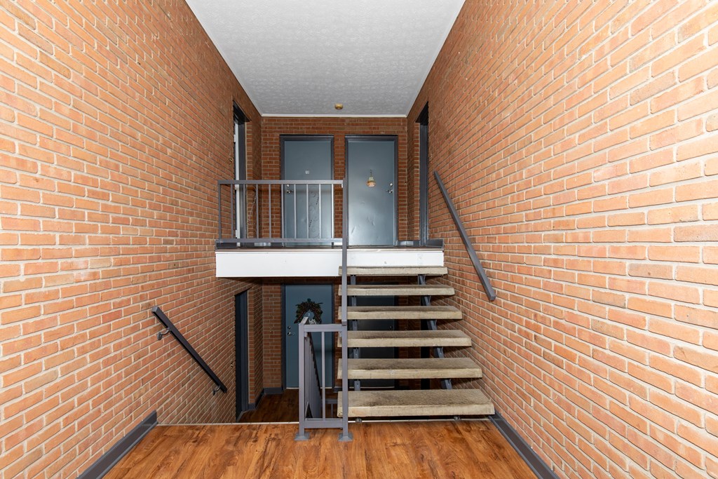a staircase with a brick wall and a glass door