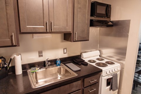 A kitchen with a white stove and a silver sink.