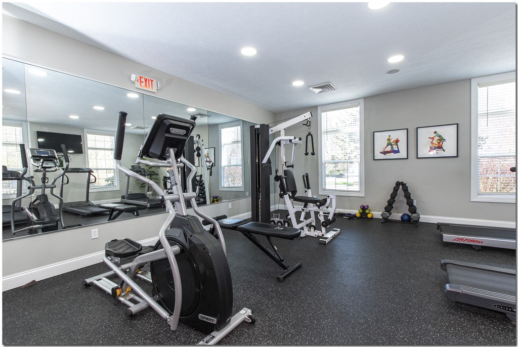 a gym with a lot of exercise equipment and mirrors on the wall