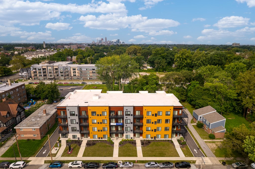 A large orange and white building with a parking lot in front. at The Lumos Apartments, Cleveland, OH, 44106