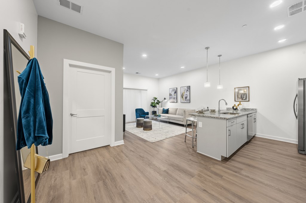 A room with a white door, a blue towel hanging on a gold rack, and a grey couch. at The Lumos Apartments, Cleveland, OH