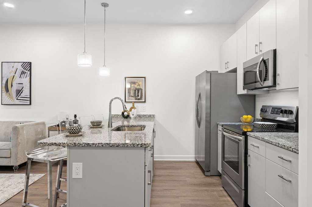 A modern kitchen with a granite countertop and stainless steel appliances. at The Lumos Apartments, Cleveland 44106