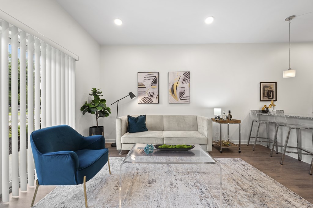 A living room with a blue chair and a white couch. at The Lumos Apartments, Cleveland