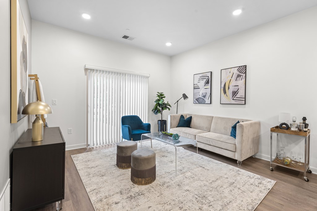 A living room with a white couch, a blue chair, and a glass coffee table. at The Lumos Apartments, Cleveland 44106
