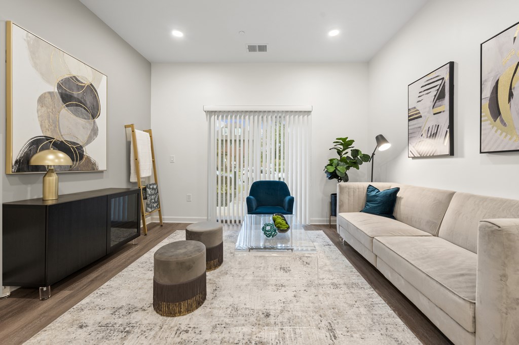 A living room with a white couch, a blue chair, and a painting on the wall. at The Lumos Apartments, Cleveland, OH