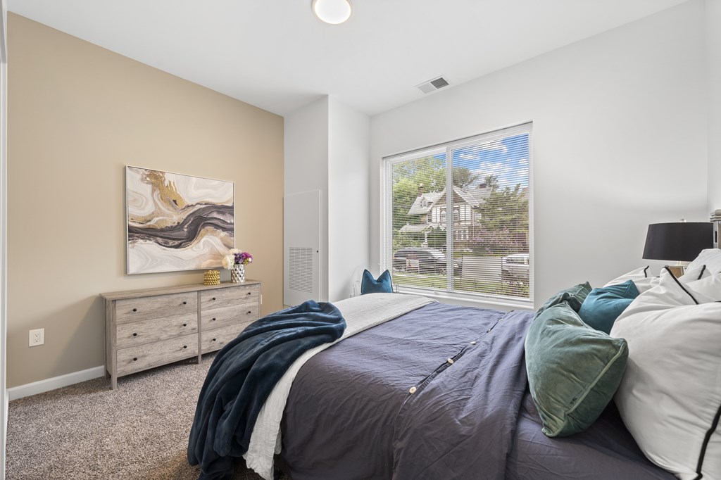A bedroom with a large bed and a painting on the wall. at The Lumos Apartments, Ohio, 44106
