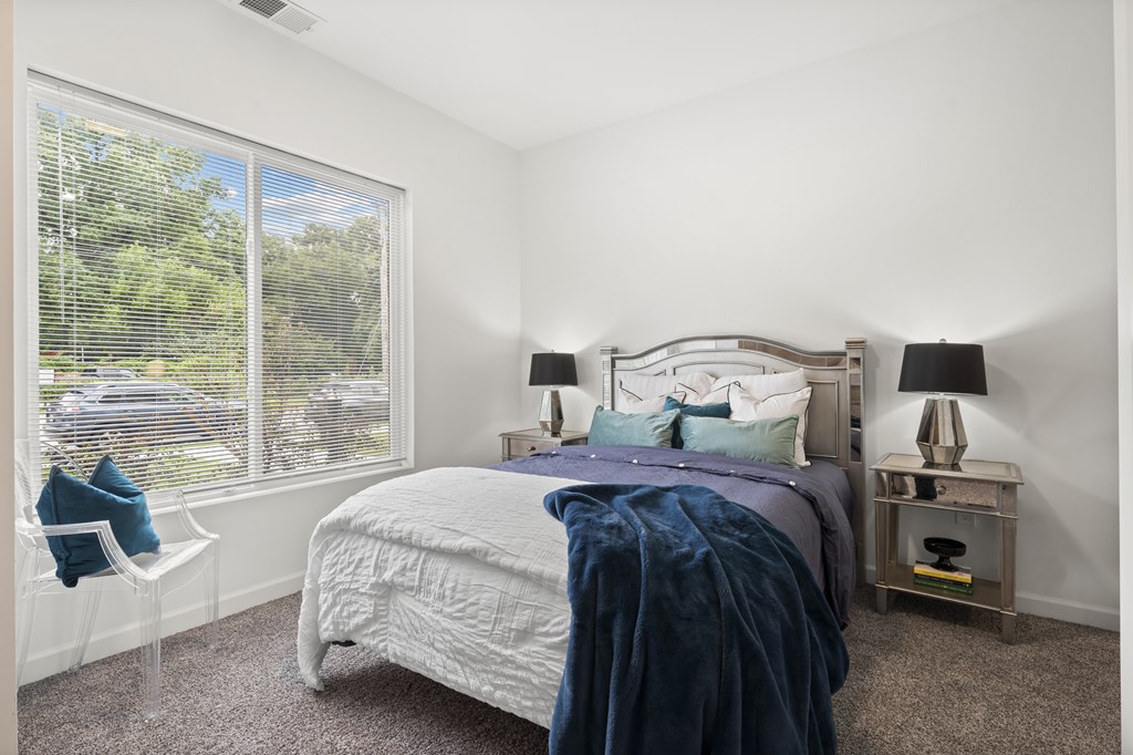 A bedroom with a large bed and a window overlooking a street. at The Lumos Apartments, Ohio