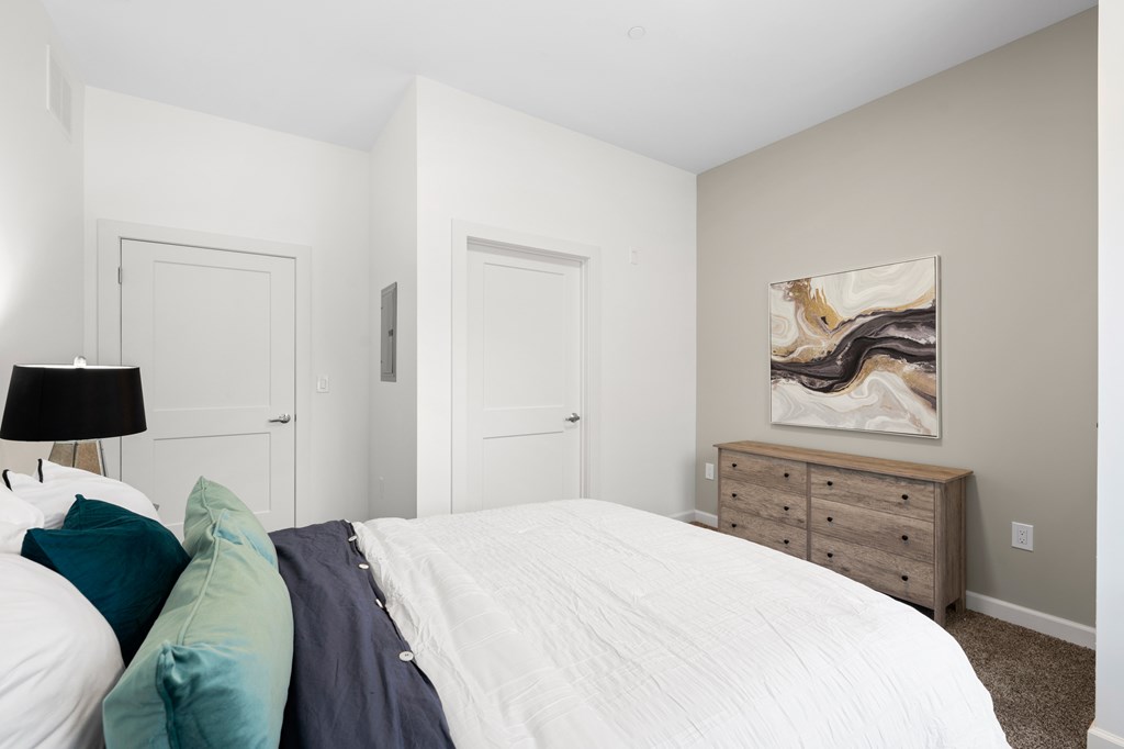 A bedroom with a white bed and a painting on the wall. at The Lumos Apartments, Cleveland