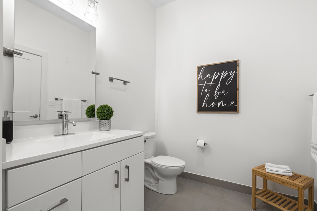 A bathroom with a white counter top and a toilet at The Lumos Apartments, Cleveland 44106