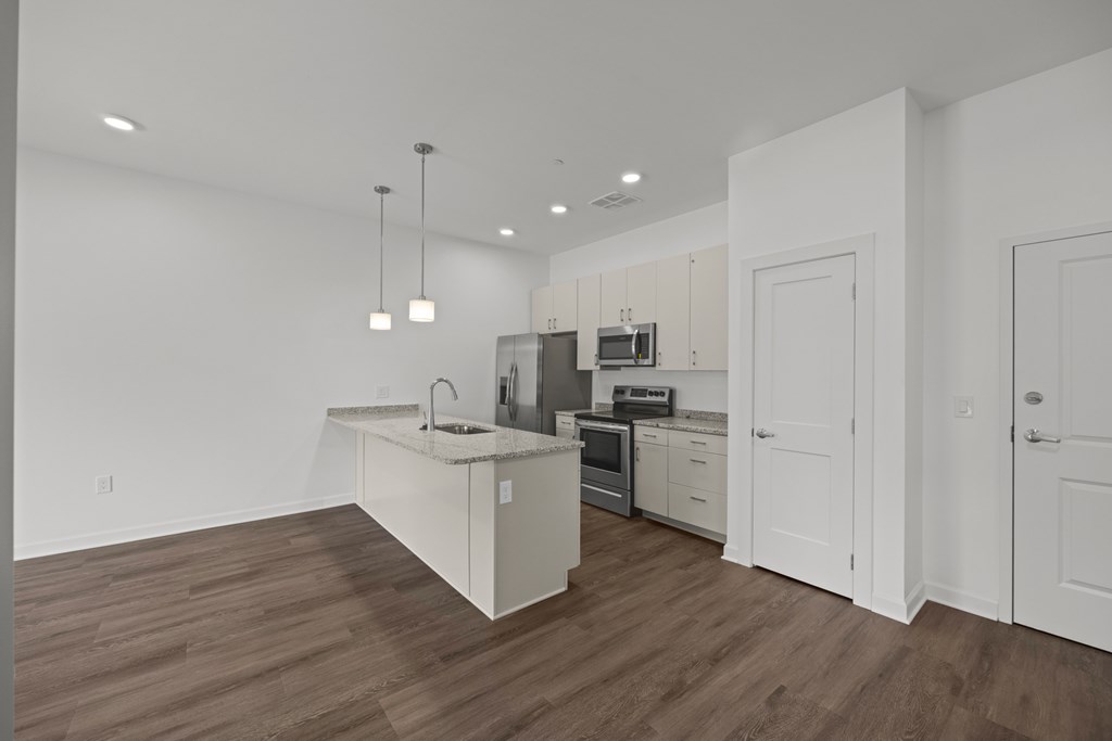 A kitchen with white cabinets and a wooden floor. at The Lumos Apartments, Cleveland, Ohio