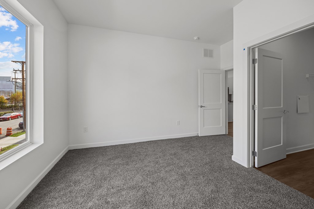A room with white walls and a grey carpet. at The Lumos Apartments, Cleveland