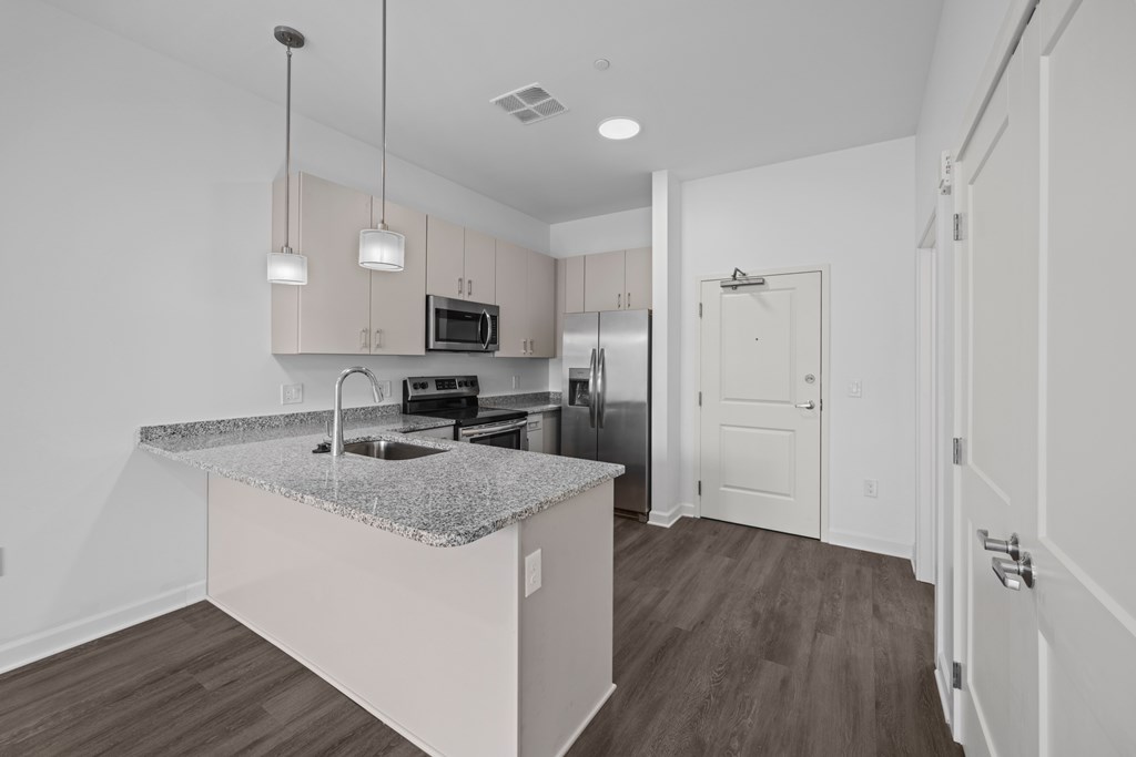 A kitchen with a granite countertop and a microwave above it. at The Lumos Apartments, Cleveland, OH